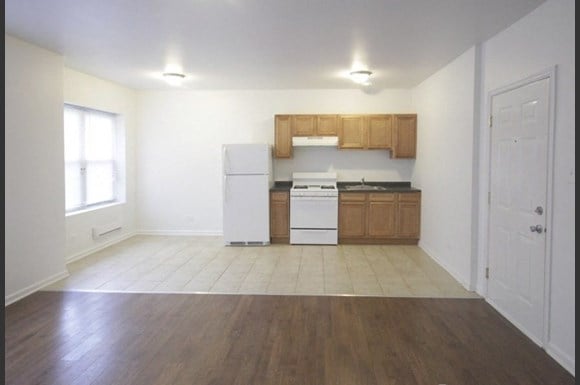 an empty kitchen and living room with wood floors and white appliances